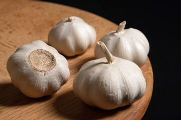 Garlic bulbs on a wooden board black background. Organic garlic, close up - 787286337