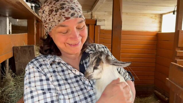 Female farmer hold at her hands little goatling baby at goat farm 