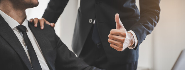 Close up view hand of boss encouraging employee by show thumb up after done good job