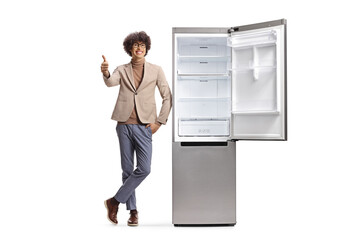 Young man gesturing thumbs up next to a new fridge