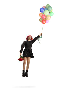 Fototapeta Woman in a black dress with red roses flying and holding a bunch of balloons