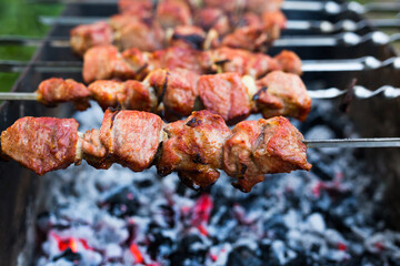 Cooking, barbecue and food concept , close up of shish kebab meat on skewers roasting on brazier grill