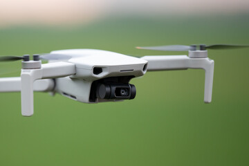 Close up of drone flying in the green field. New quadcopter in use, shooting video in good quality