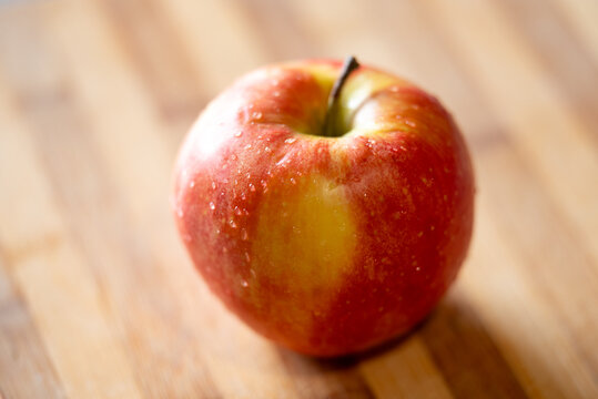 Red apple lying on the table on the sunshine, close up. Food, fruit, vitamin, nutrition concepts