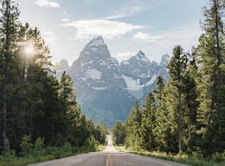 An open road leads to the Grand Teton's mountain range, rising in the distance. Trip concept.