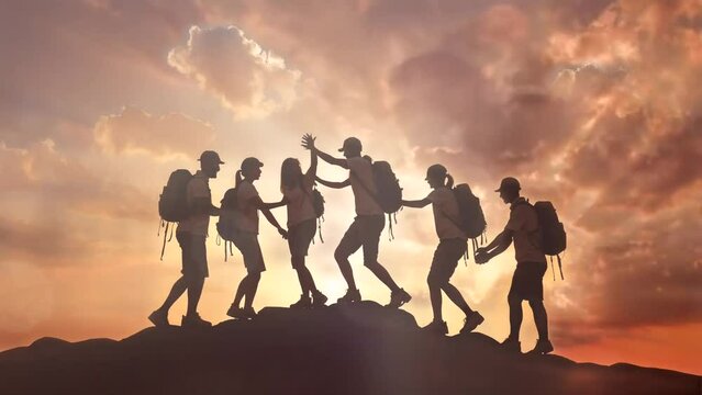 a group of people were on top of the mountain. teamwork. at sunset