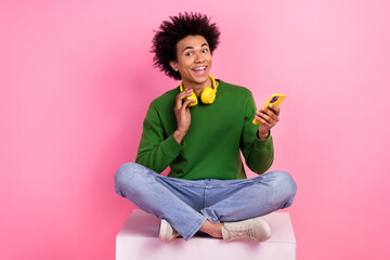 Photo of excited millennial guy sit podium use cellphone enjoy listen music isolated pastel color...