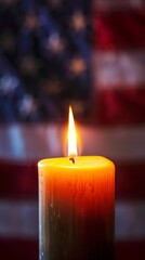 A single candle with a bright flame stands solemnly before an American flag, evoking the spirit of Memorial Day.