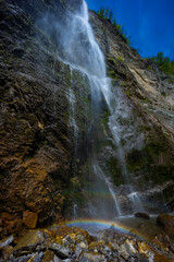 Waterfall hidden inside the forest, beauties of Slovenia to be discovered. Near Nova Gorica, Tolmin village. Water spray and vivid rainbow forms from the waterfall that falls sheer onto the rock.