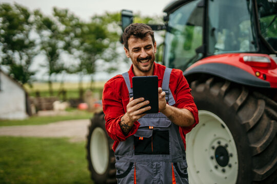 Portrait of an agronomist with a tablet in front of the agricultural machine
