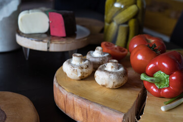 Dish ingredients on dark table: cheese, mushrooms, pepper,tomatoes