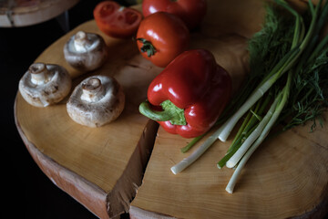 ingredients on dark table of kitchen: mushroom, pepper, fresh green, tomatoes