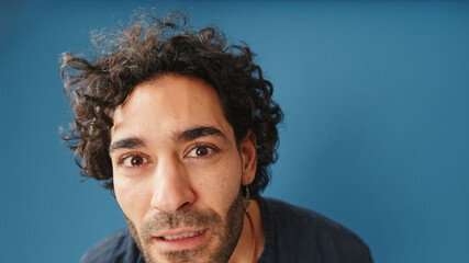 Close-up, man with curly hair, wearing blue shirt, looking at camera looking for something isolated...