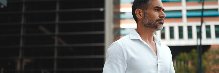 Close up of mature businessman with neat beard wearing white shirt leaves the office in the...