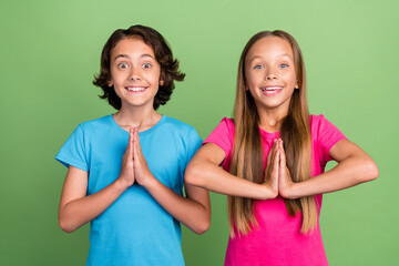 Photo of charming excited friends wear t-shirts arms togher praying isolated green color background - obrazy, fototapety, plakaty