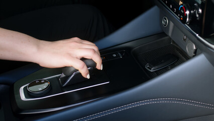 Business woman in her new modern car presses the start button. A middle-aged woman is happy to buy...