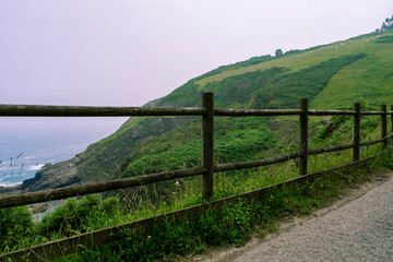 Fototapeta na wymiar mountain trail enclosed by a wooden fence next to the Atlantic Ocean.