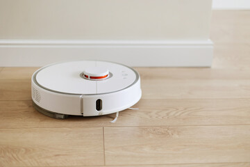 Wireless autonomous smart robot vacuum cleaner is vacuuming floor with modern tiles at living room....