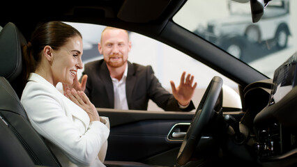 A male manager helps a businesswoman choose a new modern electric car. The concept of advertising...