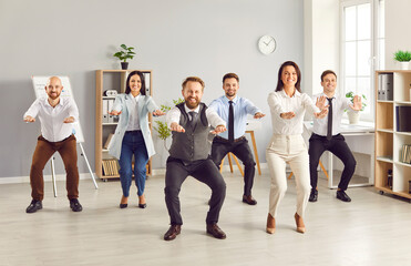 Team of businesspeople is exercising and stretching with smiles and in good mood during a work...