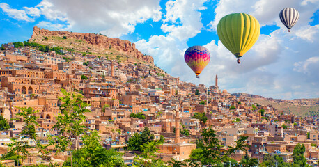 Hot air balloon flying over Mardin old town with bright blue sky - Mardin, Turkey