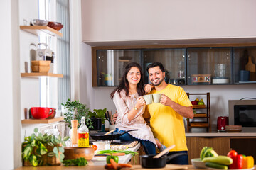 Asian Indian Young couple having coffee together at home in the kitchen.