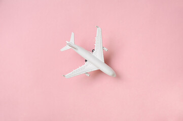 Airplane with passport and tickets on the bright sunny pink background. Vacation travel concept.