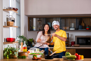 Indian couple in kitchen - Young Beautiful asian wife enjoying cooking with husband.