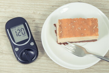 Glucometer with high result sugar level and portion of sweet cheesecake. Nutrition during diabetes