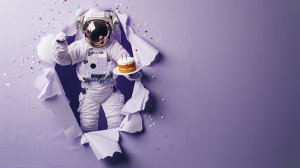 Celebrating space-style, an astronaut leaps through violet paper with a cake adorned with lit candles