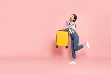 Happy Asia woman traveler standing and holding suitcase isolated on pink background, Tourist girl having cheerful holiday trip concept, Full body composition