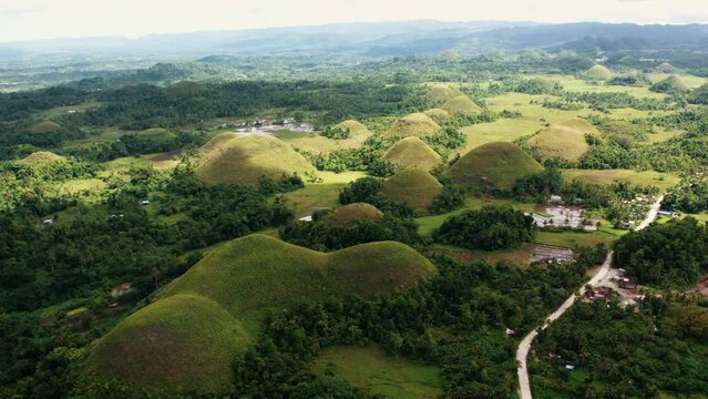 Chocolate Hills aerial view, sunny green valley with mountains. Wild nature landmark in Bohol, Philippines. Concept of wanderlust, place for hiking, traveling