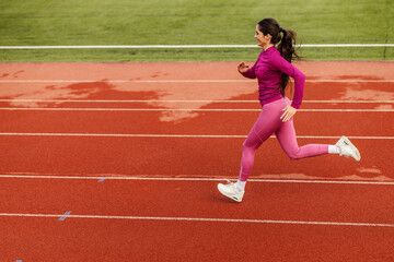 A fast sportswoman is sprinting at stadium.
