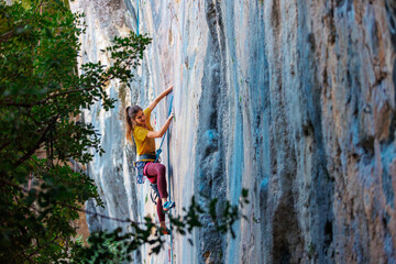 The girl climbs the rock. The climber trains on natural terrain. Extreme sport.  A woman overcomes...
