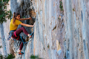 A young and strong woman is rock climbing on a rock. .