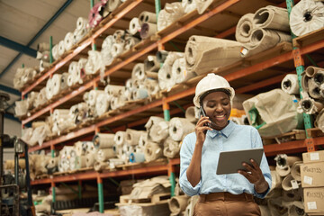 Fototapeta na wymiar African woman with a tablet and phone standing in a warehouse