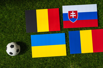 Belgium Leads Group E: Flags of Belgium, Slovakia, Romania, Ukraine, and soccer ball on green grass...