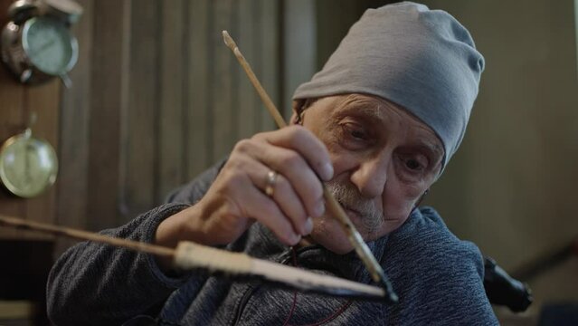 Elderly male master works in his workshop restoring japanese deba knife sheath