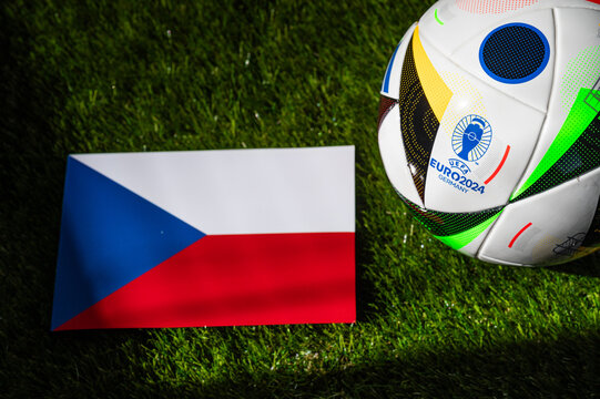 Czech Republic national flag and official soccer ball of Euro 2024 football tournament in Germany placed on green grass. Black background, edit space