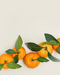 Top view juicy orange yellow tangerines with green leaf, Natural citrus fruit flat lay minimal style, light  beige background. Organic, healthy, vegetarian and plant-based food concept, pastel tone