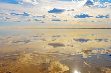 Scenic sunlight landscape, shore of salt lake, water surface and reflections sky with clouds....