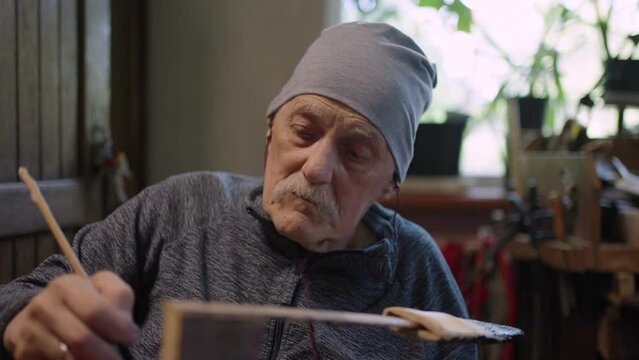 Elderly male master works in his workshop restoring japanese deba knife sheath