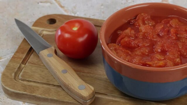 bol de tomates concass&eacute;es, en gros plan, sur une planche &agrave; d&eacute;couper