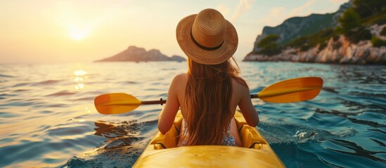 Sunset kayaking adventure, young woman in straw hat paddling in pristine blue sea, outdoor travel