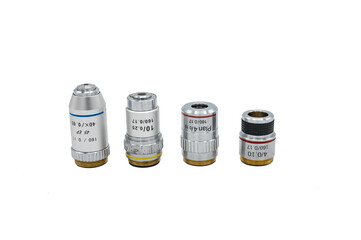 Detail of a set of four microscope lenses on a white background, there are approach and immersion...