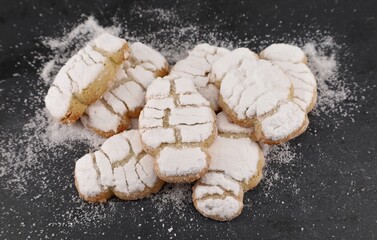 Freshly made Mandorlini. They are traditional italian almond cookies covered with powdered sugar on black stone countertop