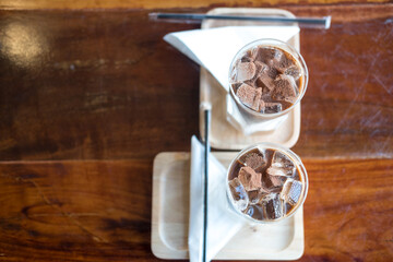 Two iced mocha coffee. Espresso coffee mixed chocolate put in ice in long glass on wooden table in cafe.
