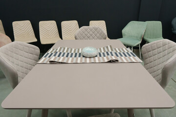 Beige wooden table complete with beige wooden chairs with soft fabric upholstery. Green saucer on the table