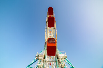 Colorful ferris wheel of the amusement park in the blue sky background.