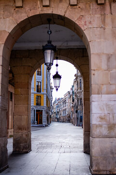 Exploring Gijón's urban center, a passage bathed in natural light, devoid of people.